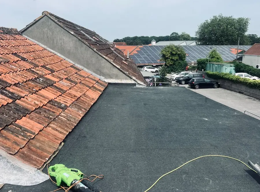 Completed felt flat roof alongside a clay tiled pitched roof